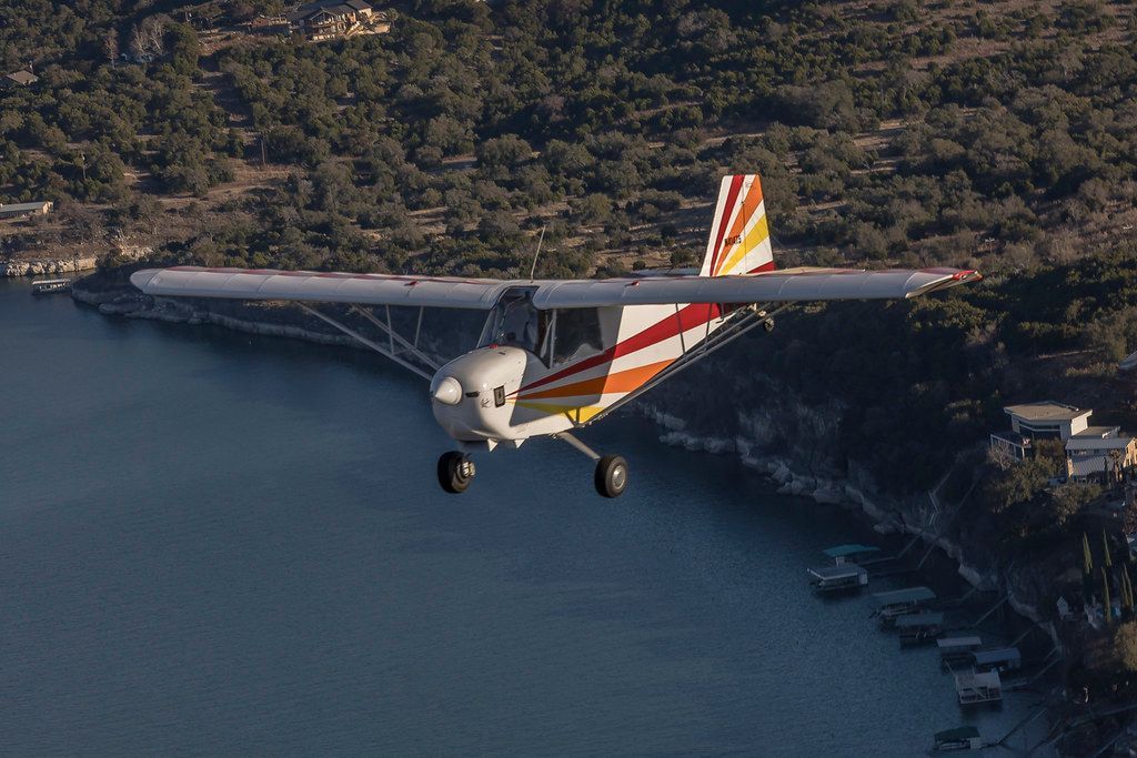 Carlson Sparrow Sport Special flying along a wooded lakeshore