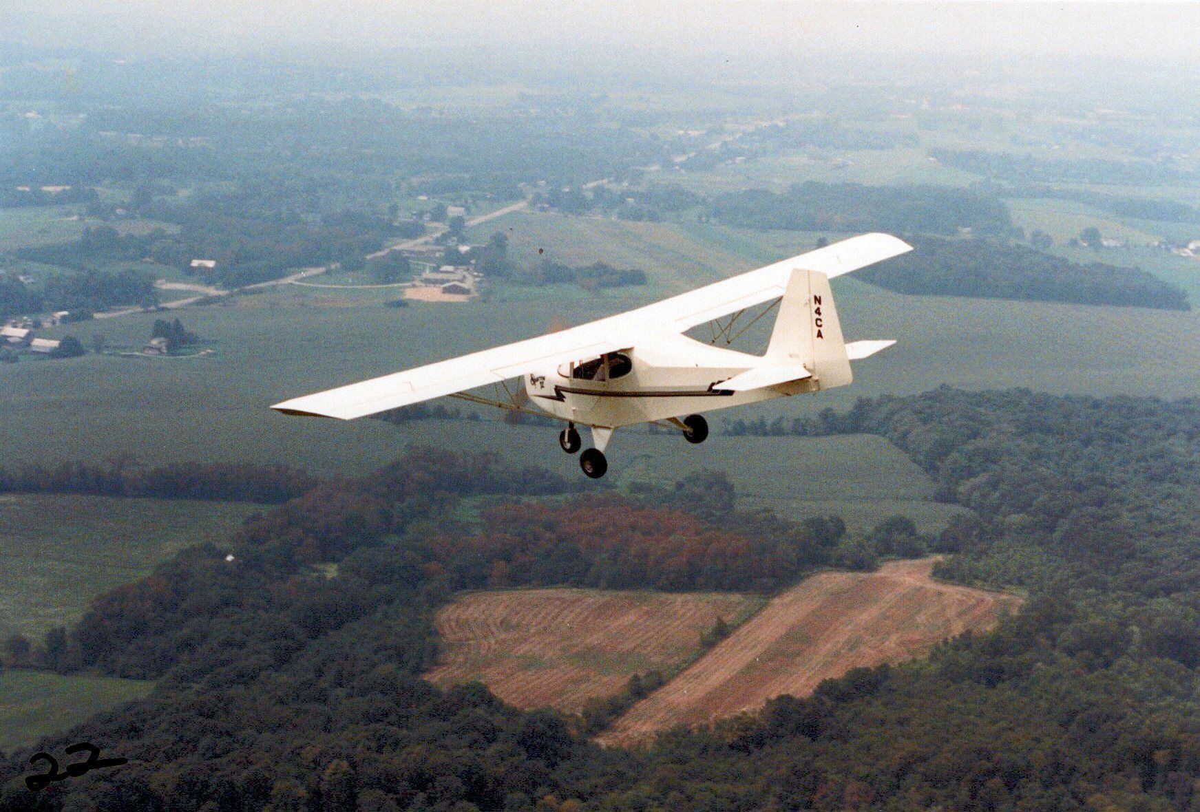 Carlson Sparrow II flying over farmland and woods