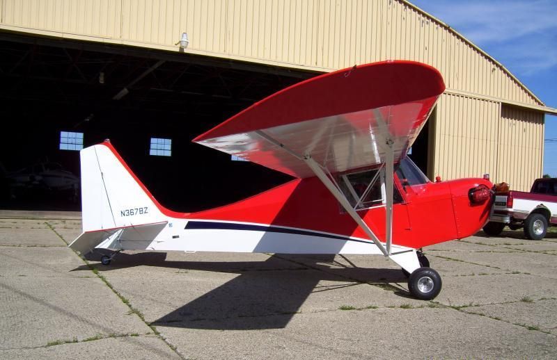 Red and white Carlson Sparrow Sport Special taildragger parked in front of a hangar